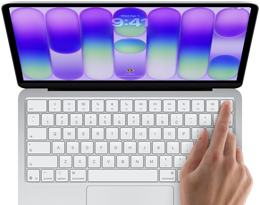 MacBook Neo, stříbrná barva, zobrazuje se přihlašovací obrazovka, něčí prst na snímači Touch ID v pravém horním rohu klávesnice